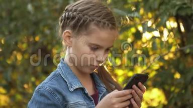 十几岁的女孩独自在苹果花园的背景下使用手机。 智能手机成瘾